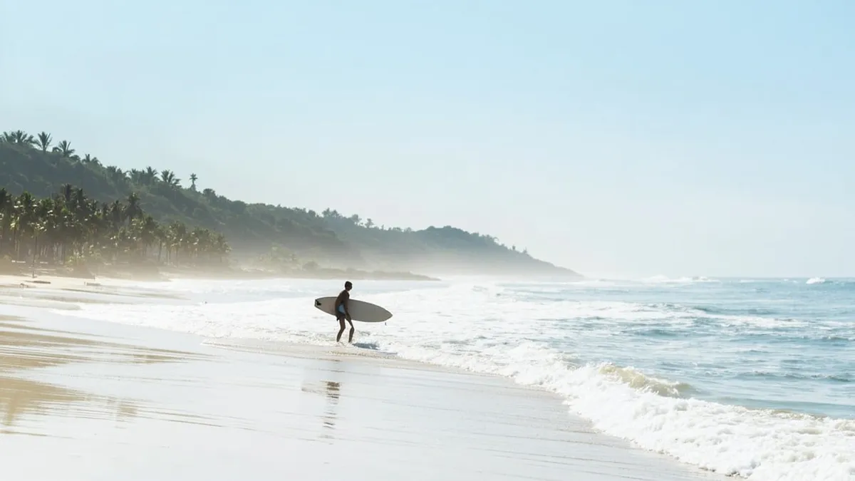 Surfer paddling into small waves at Serenity Beach near Pondicherry on a calm December morning.
