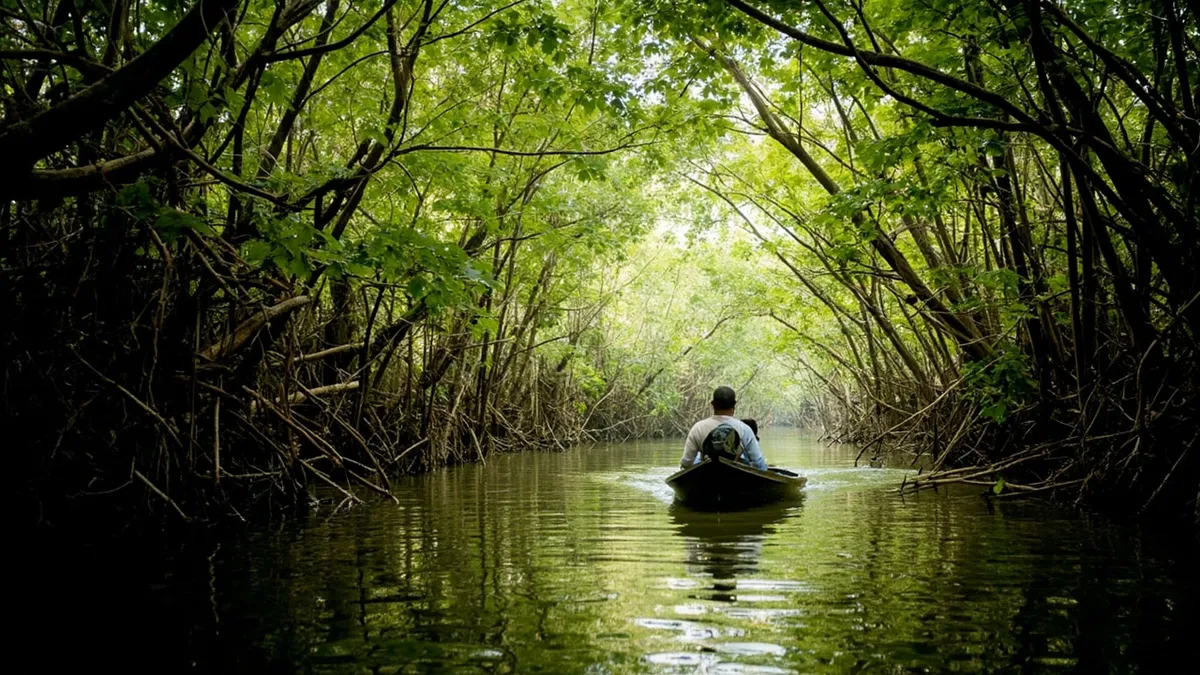Boat moving through narrow mangrove channel with tangled roots and green canopy light.