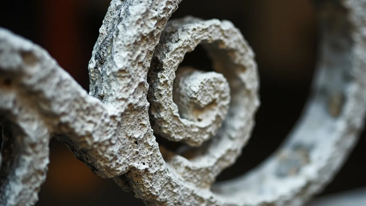 Thick layered paint packed into the scrolls and joints of a Victorian wrought-iron gate.
