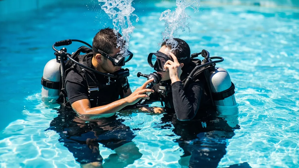 Beginner diver practicing scuba skills in a training pool with an instructor in Pondicherry.