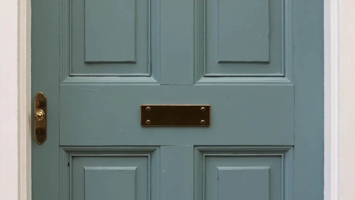 Four-panel Victorian front door painted in a heritage colour, set into a stone porch surround.