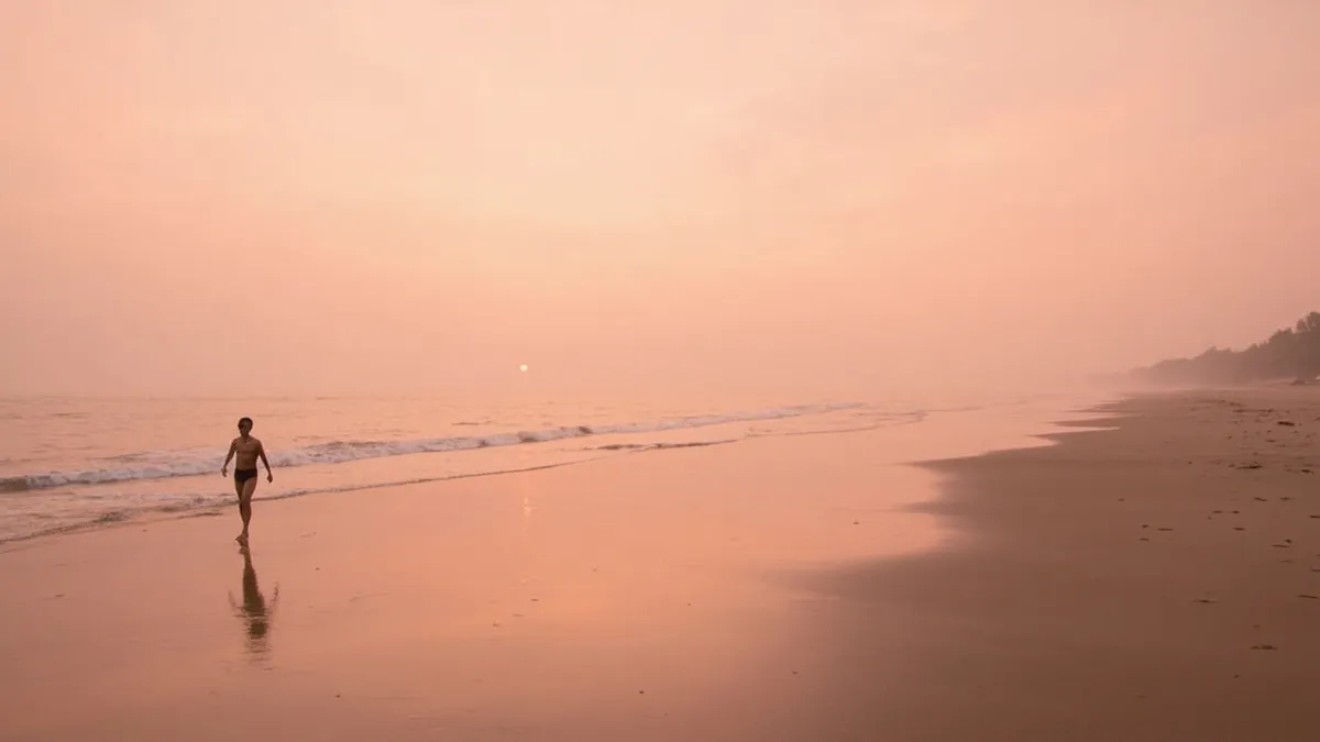 Sunrise over the empty Bay of Bengal shoreline at Auroville Beach with pink and gold skies.