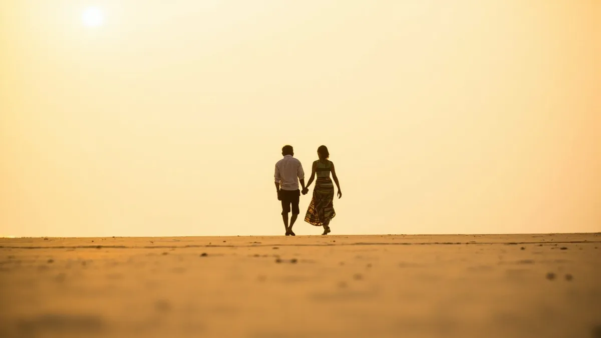 Couple walking on a quiet Pondicherry beach at sunrise.
